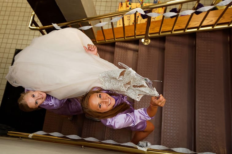 Bridesmaids carry wedding dress upstairs